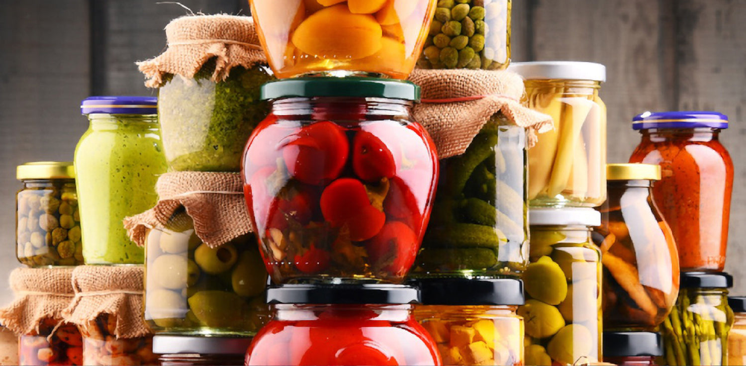 Fermented fruits in jars - A photo of jars filled with various types of fermented fruits. The fruits may include items such as berries, cucumbers, carrots, or cabbage that have undergone fermentation in a brine or pickling solution. The jars may be glass or ceramic, and the fermented fruits may be visible through the glass. The fruits may appear soft, changed in color, and may have bubbles or other signs of fermentation, indicating the preservation process. 